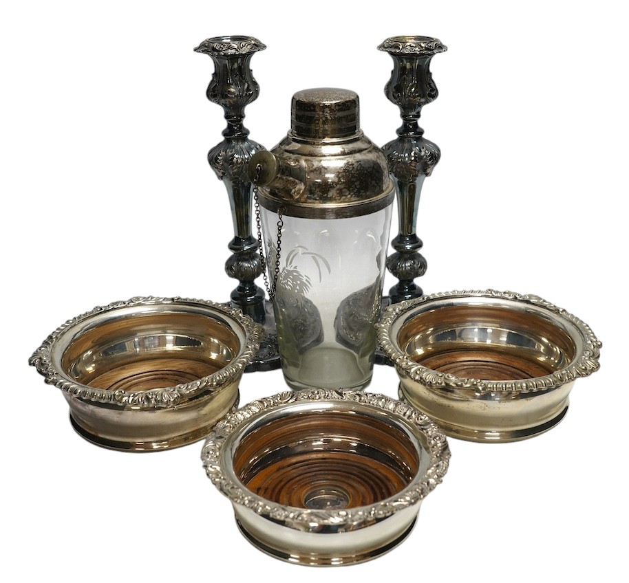 A pair of silver plated candlesticks, a pair and another wine coaster, and a cocktail shaker, tallest 25cm. Condition - fair